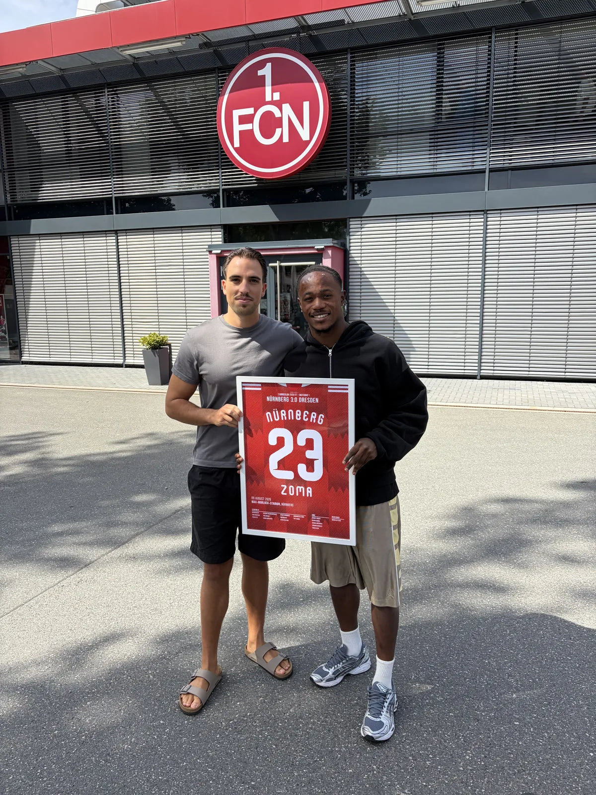Gerahmtes Nürnberg-Poster in Kundenhand vor dem Stadion des 1. FCN